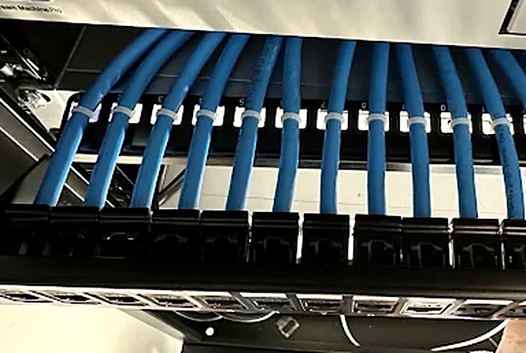 Neatly dressed blue network cabling terminated into a patch panel by Kalieb Designs