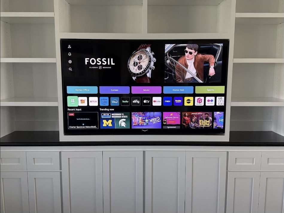 Large TV mounted inside custom white built-in cabinets by Kalieb Designs, wires fully concealed