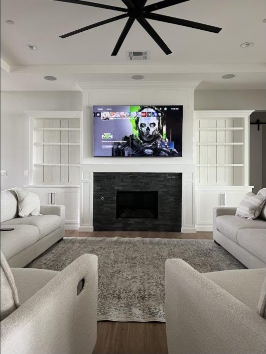 TV mounted above a stone fireplace by Kalieb Designs